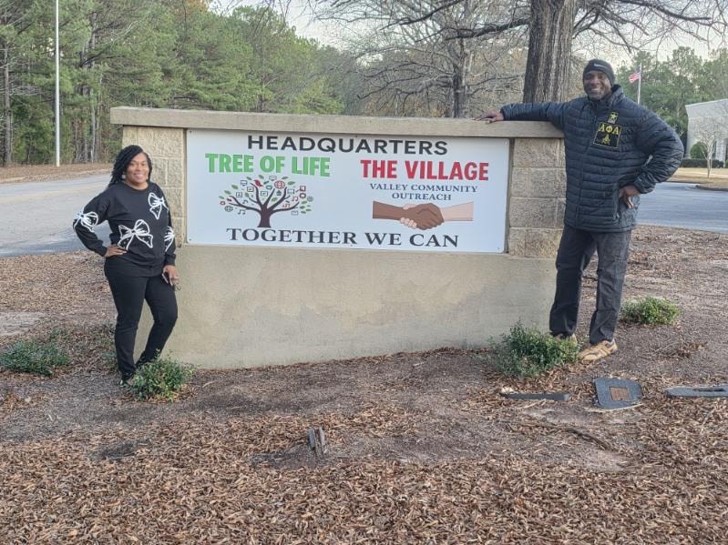 Jennifer Hughley Grier and Clint in front of the Tree of Life facility sign